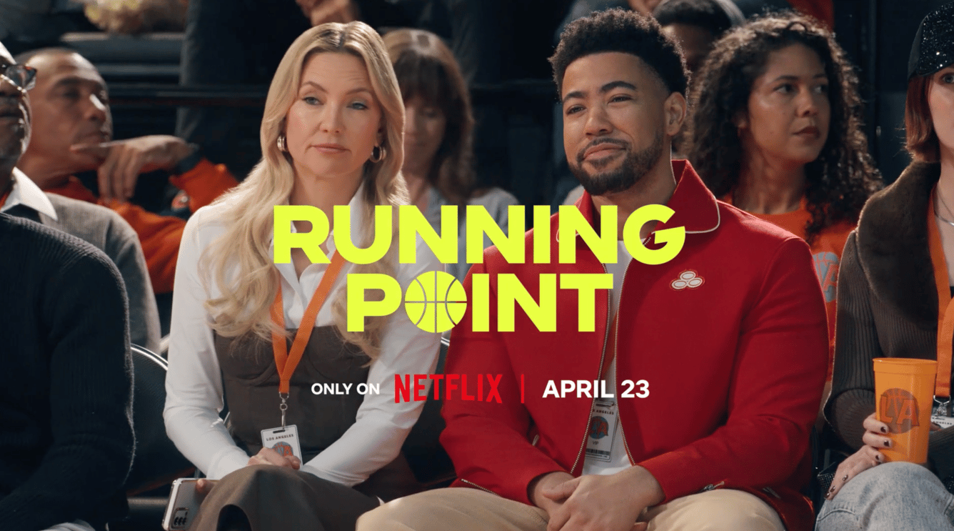 Kate Hudson and Jake From State Farm sitting next to each other on a basketball court in Running Point ad.